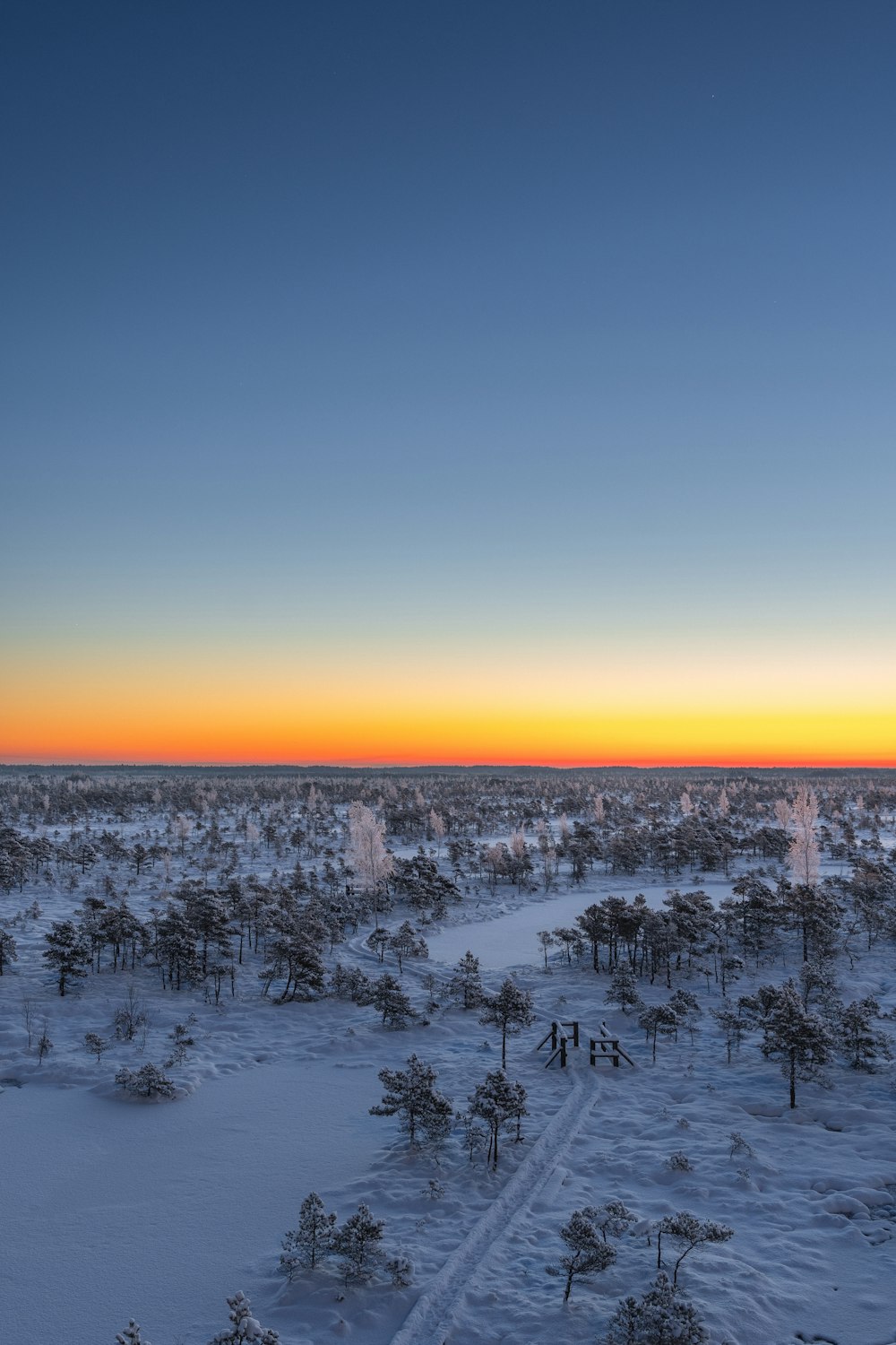 the sun is setting over a snowy landscape