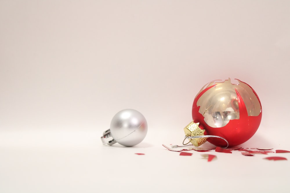 ein rot-silberner Weihnachtsschmuck neben einem silbernen Ornament