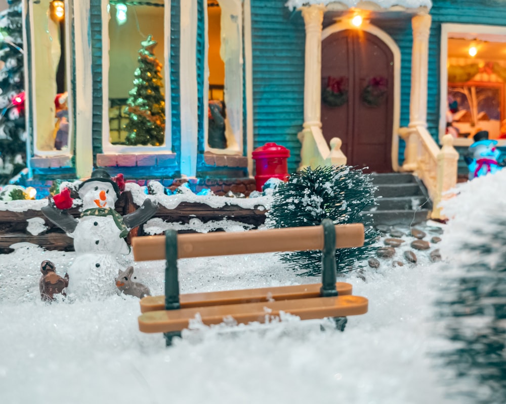 um boneco de neve está na frente de uma casa azul