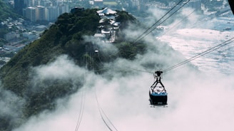 a cable car going up a mountain with a city in the background