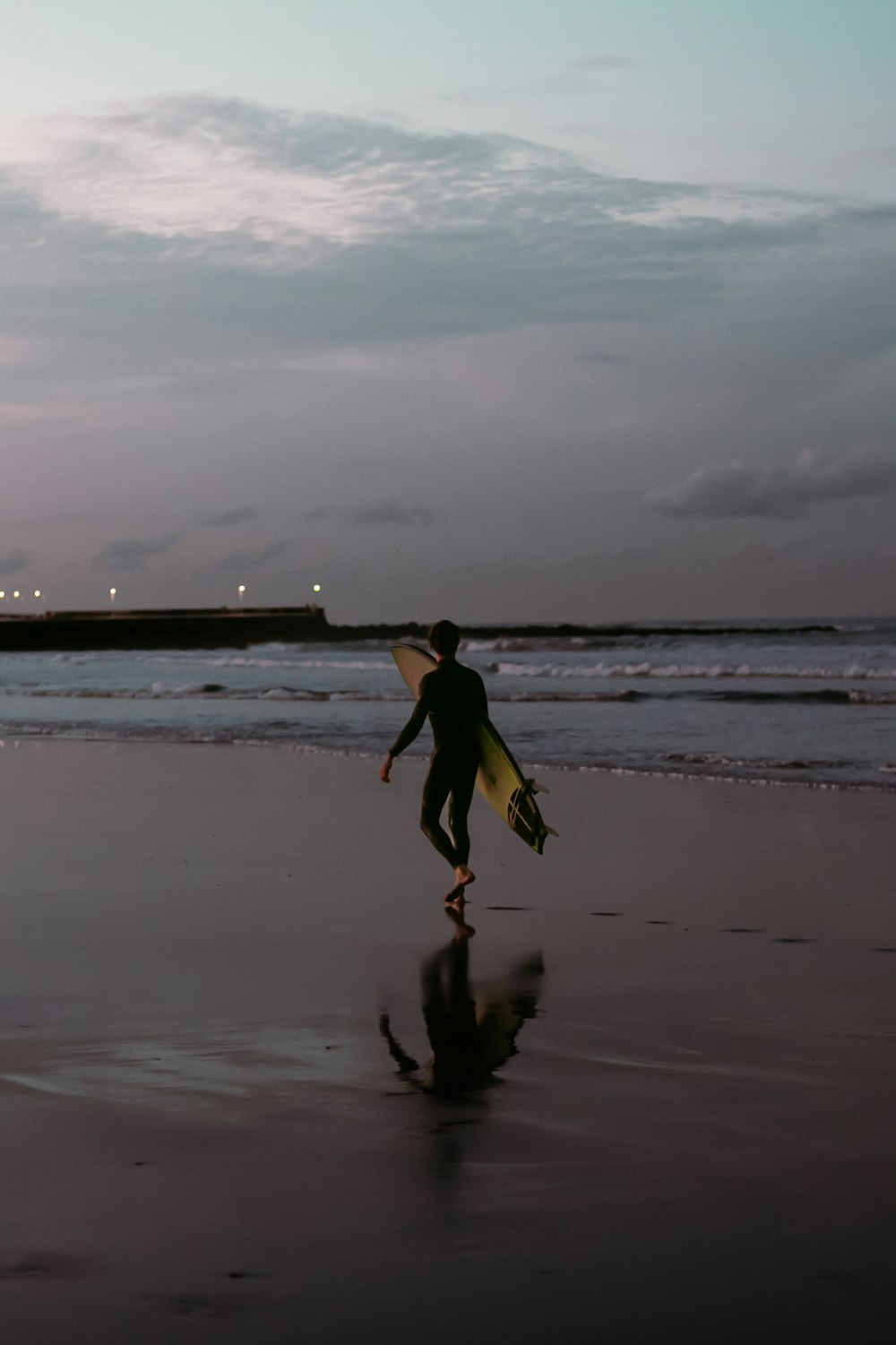 a person walking on a beach with a surfboard