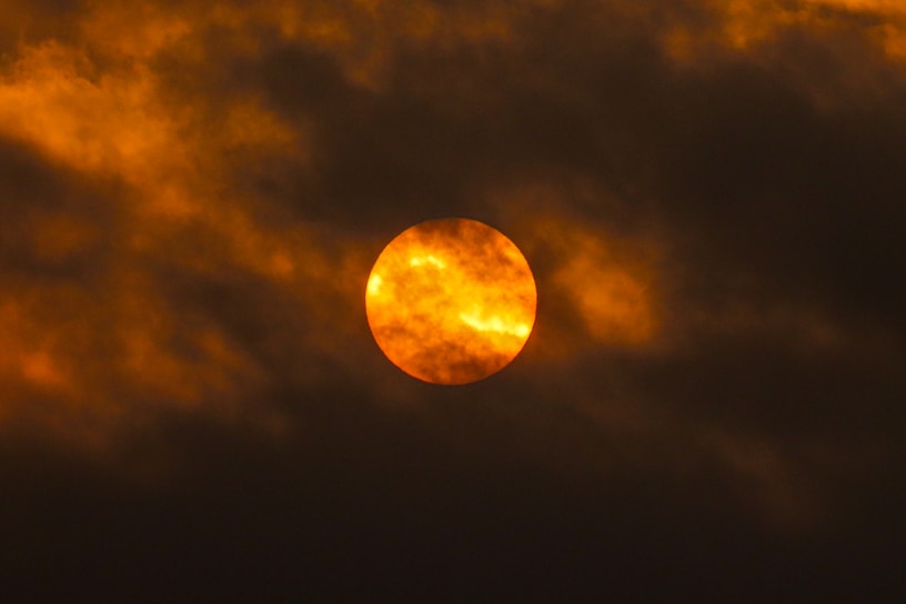 Close-up of the sun's fiery surface with swirling solar flares in vibrant orange and yellow hues.