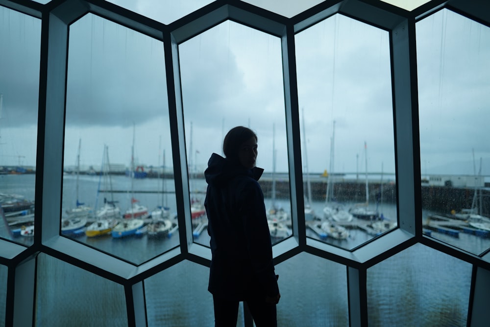 a person looking out a window at a harbor
