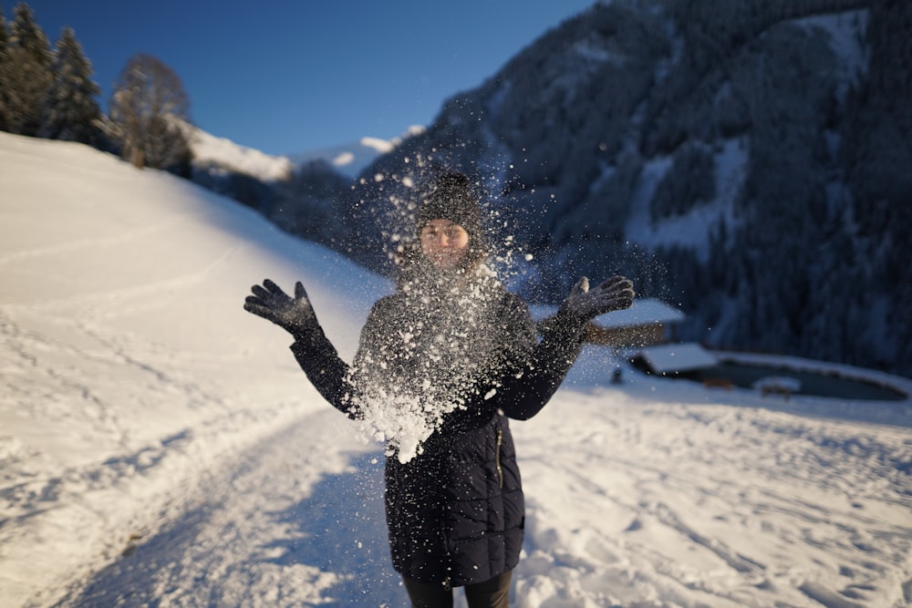 a person standing in the snow throwing snow in the air
