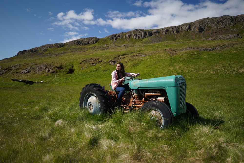 a woman riding on the back of a green tractor