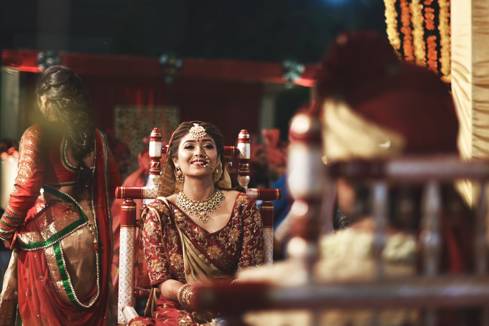 a woman in a red and gold outfit sitting in a chair