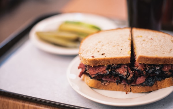 A roast beef sandwich on a plate with pickles