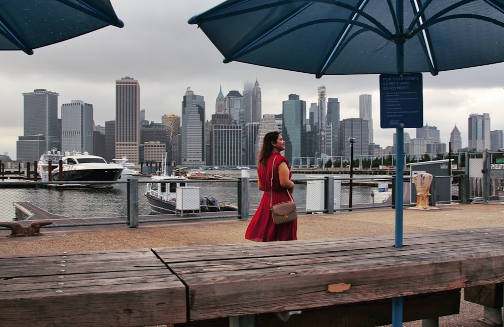 a woman in a red dress standing on a pier