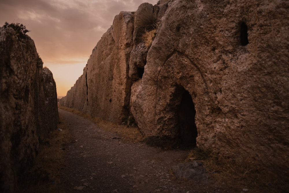 a path between two large rocks with a sky in the background