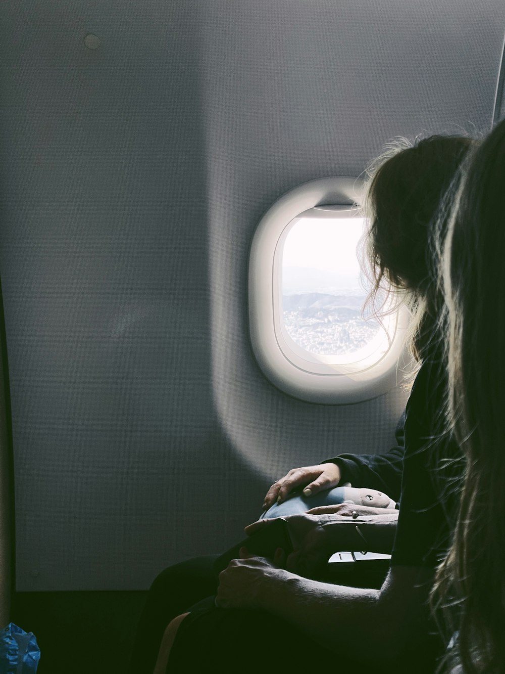 uma mulher sentada em um avião olhando pela janela