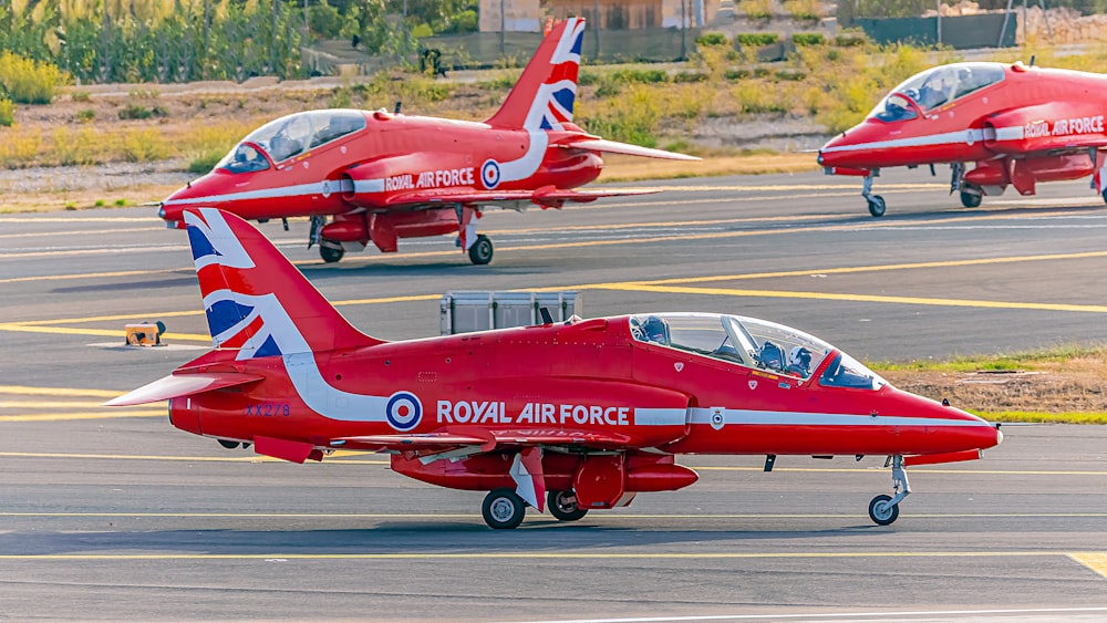 a group of red fighter jets sitting on top of an airport tarmac