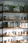 A set of wooden wall-mounted shelves holding decorative items and books.
