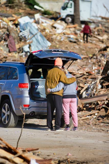 A driver shaking hands with a rescue operator beside a recovered vehicle.