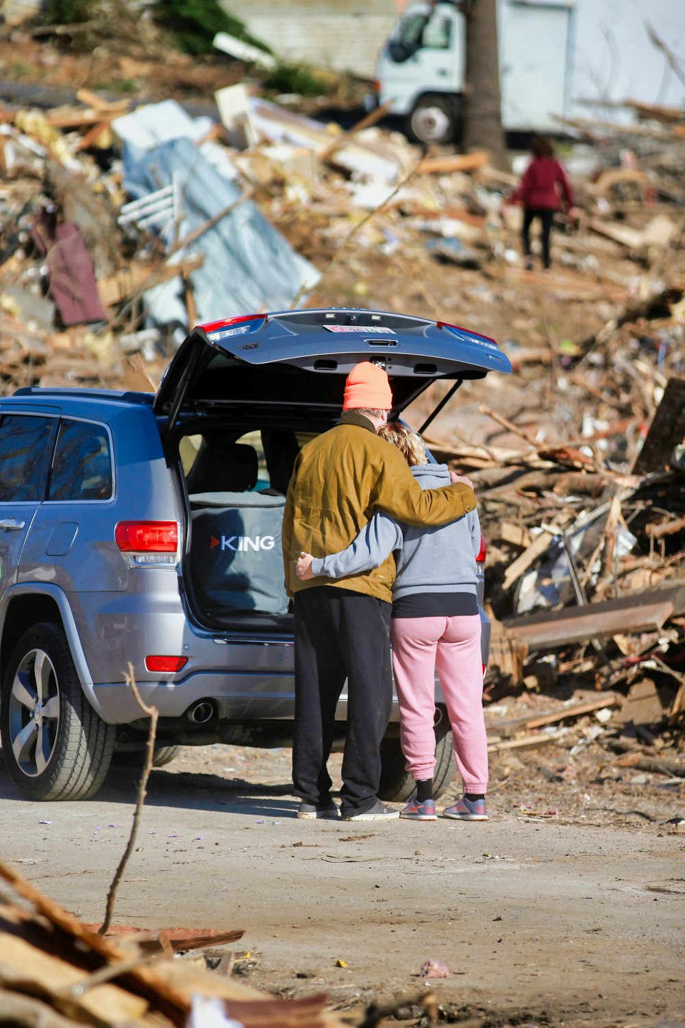 Un par de personas de pie junto a un coche