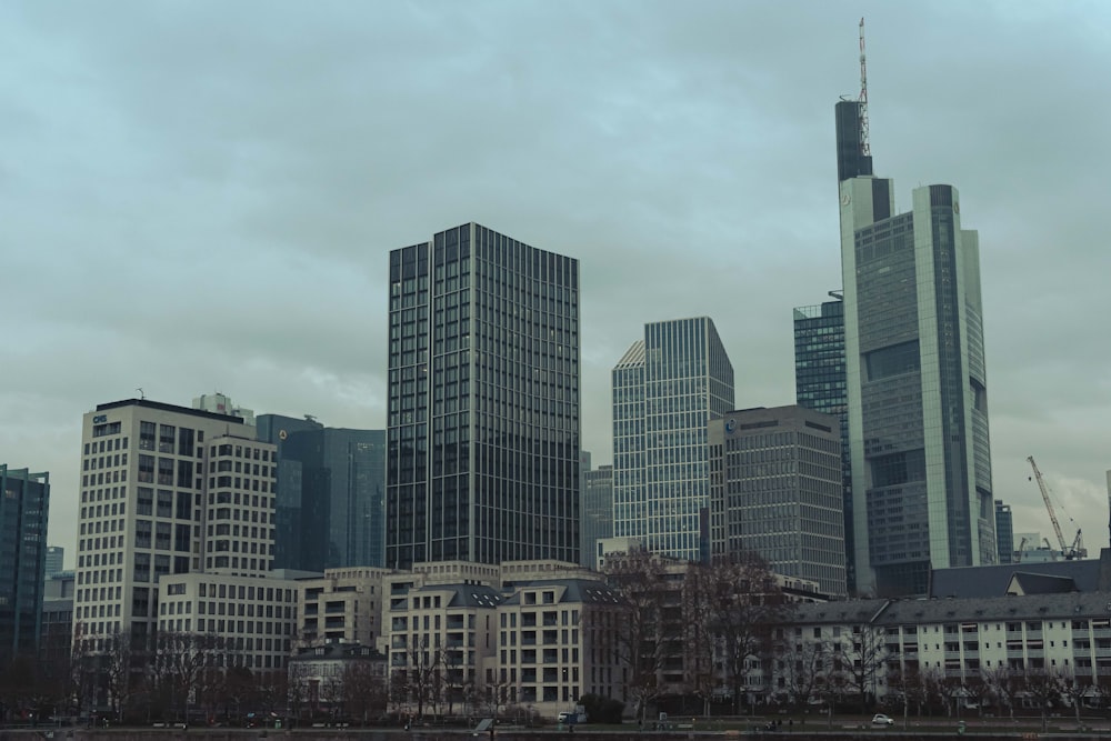 a city skyline with tall buildings and a body of water