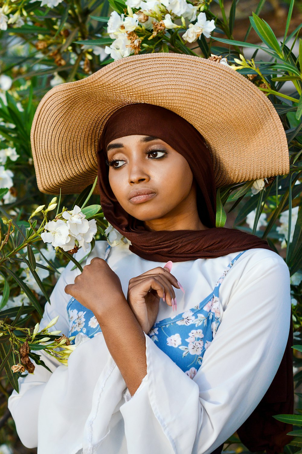 a woman wearing a straw hat and holding a flower