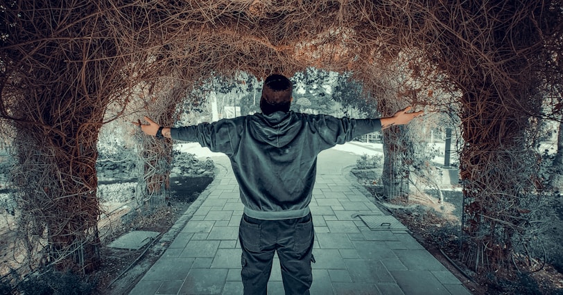 a man standing in a tunnel of vines