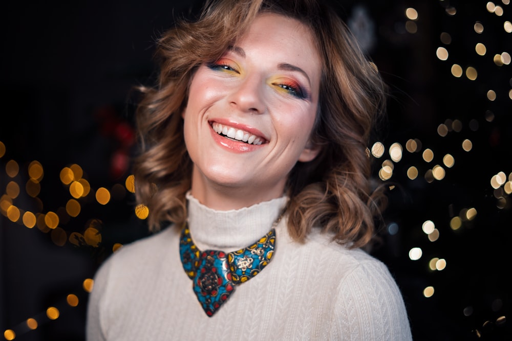 a woman wearing a white sweater and a colorful necklace