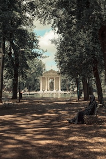 a person sitting on a bench in a park
