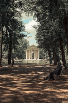 a person sitting on a bench in a park
