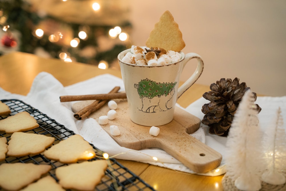 a cup of hot chocolate with marshmallows and a pine cone