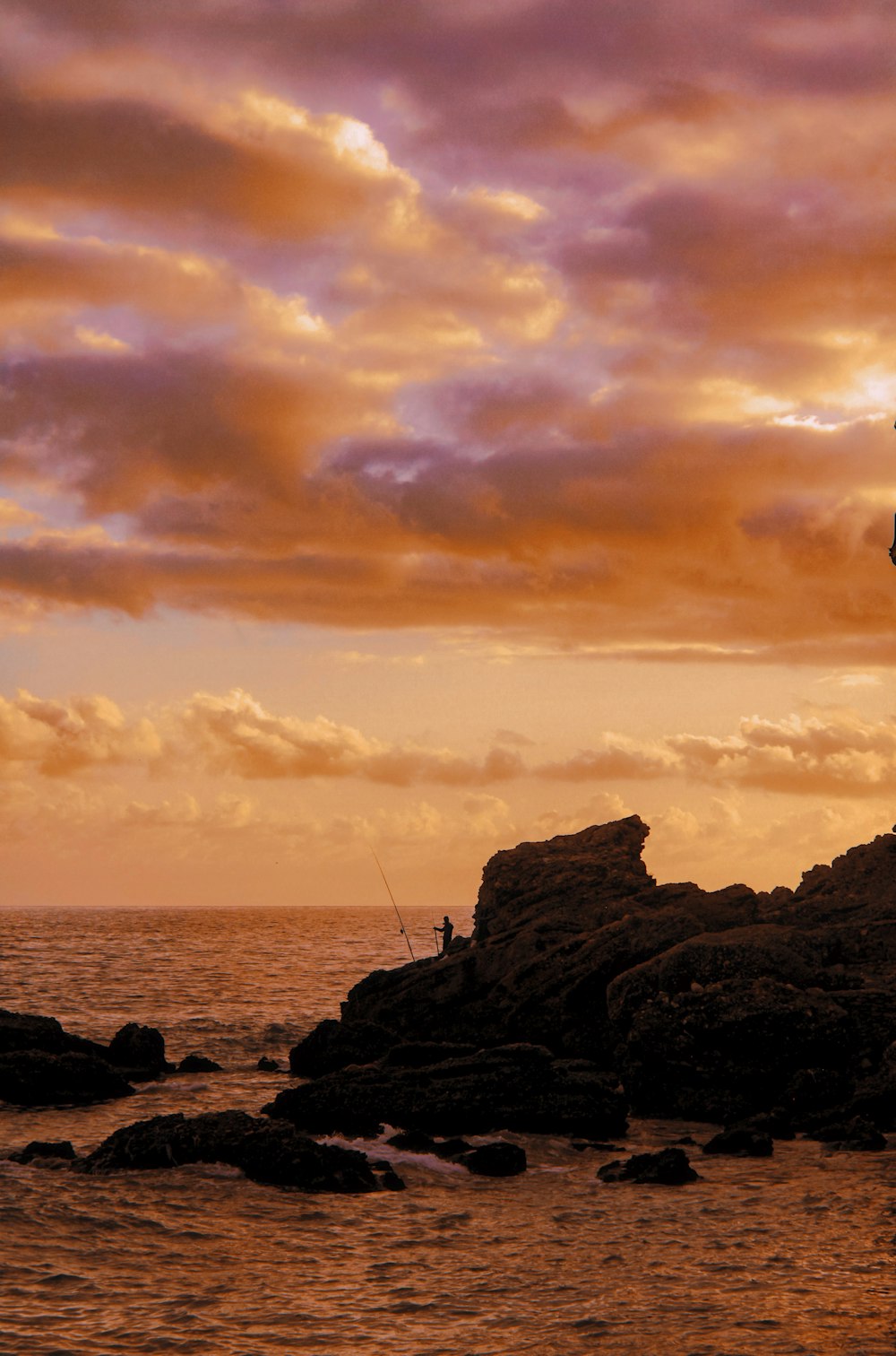 a man standing on top of a rock next to the ocean