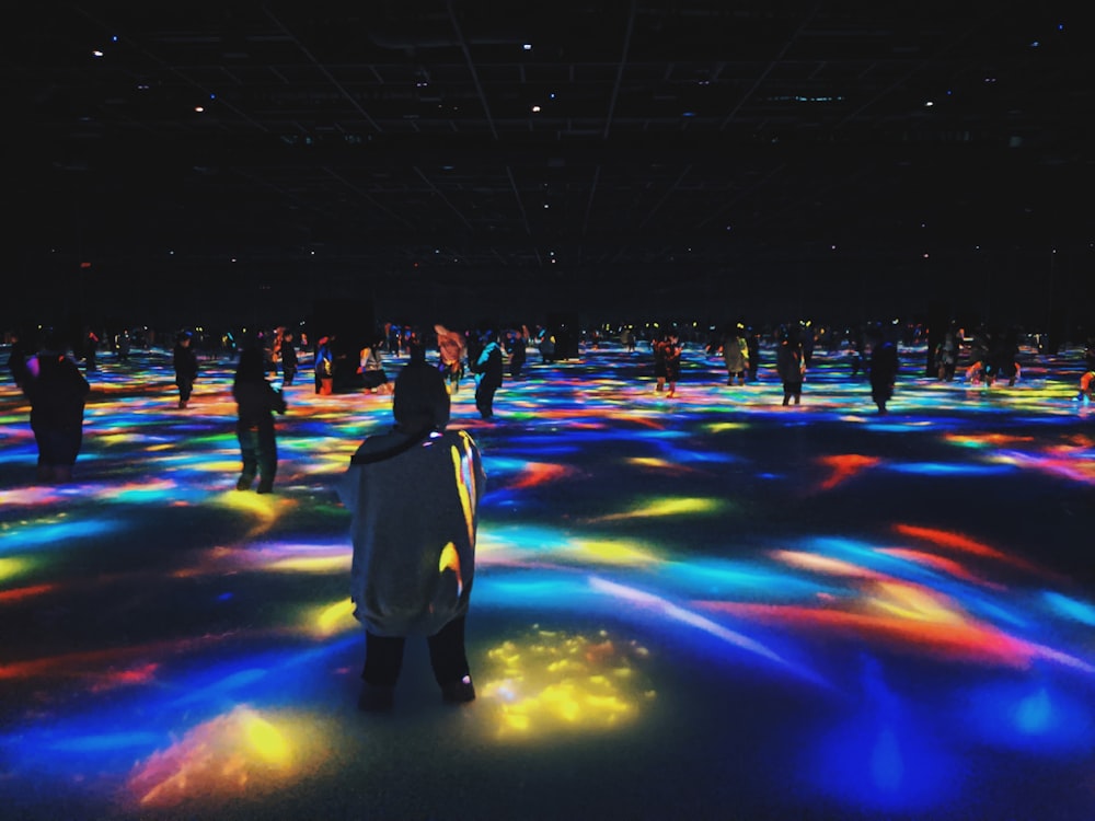 a group of people standing around a room filled with colorful lights