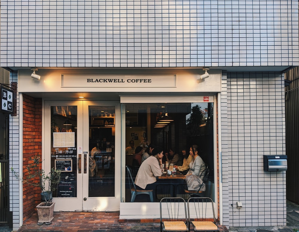 a group of people sitting at a table outside of a coffee shop