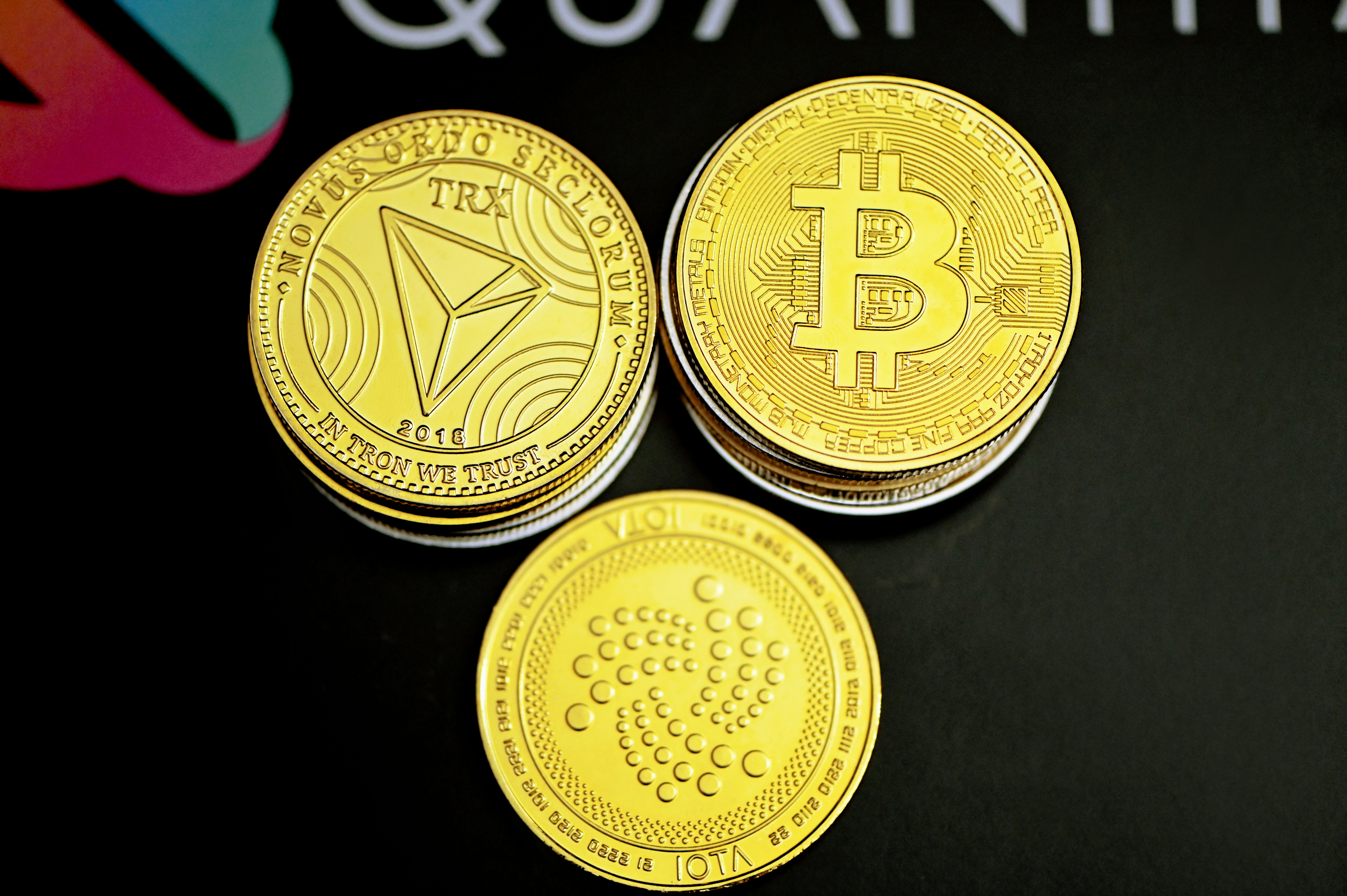 Tron coin, Bitcoin, and IOTA coin are together on the Quantitatives background