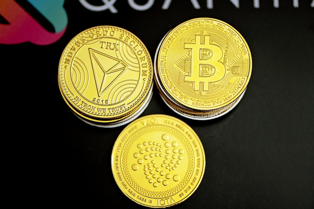 three gold bitcoins sitting on top of a black table