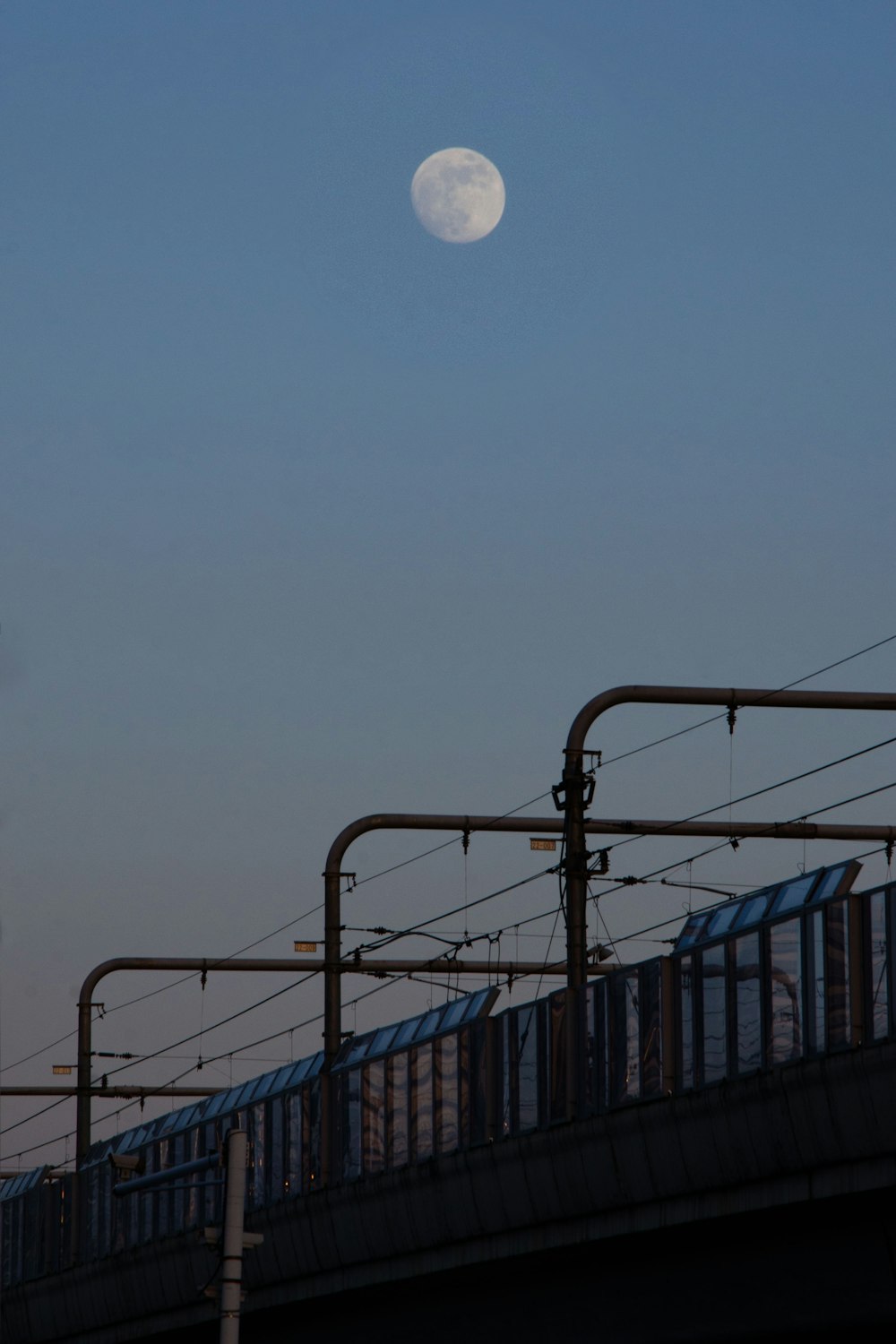 a train traveling over a bridge under a full moon