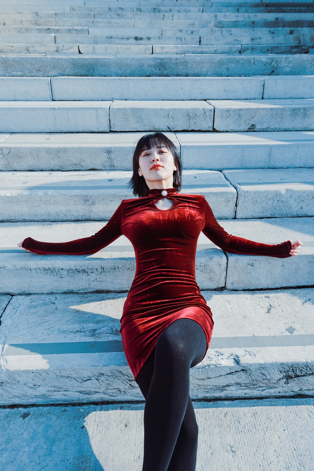 a woman in a red dress sitting on some steps