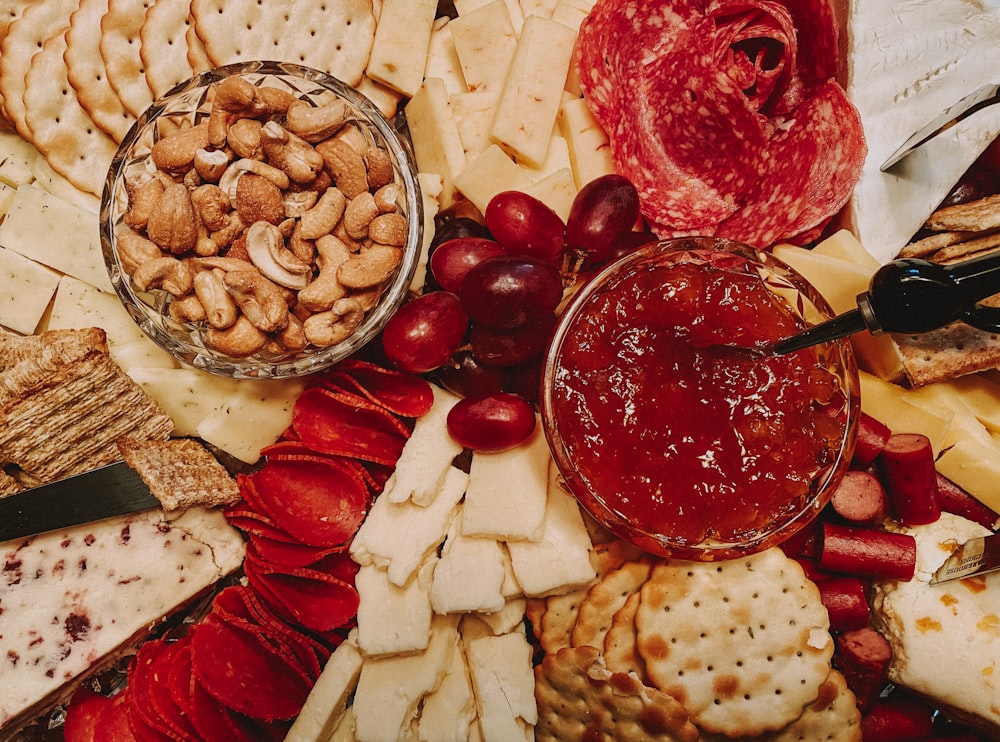 a variety of cheeses, crackers, and meats on a platter