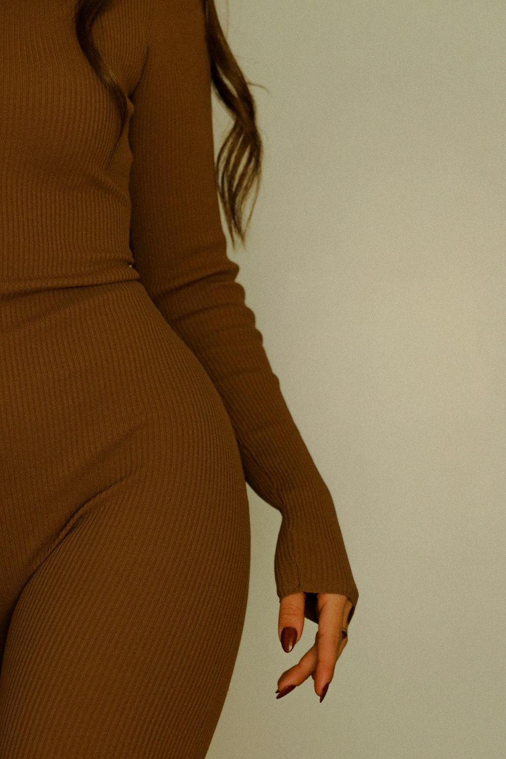 a woman in a brown bodysuit with her hands on her hips
