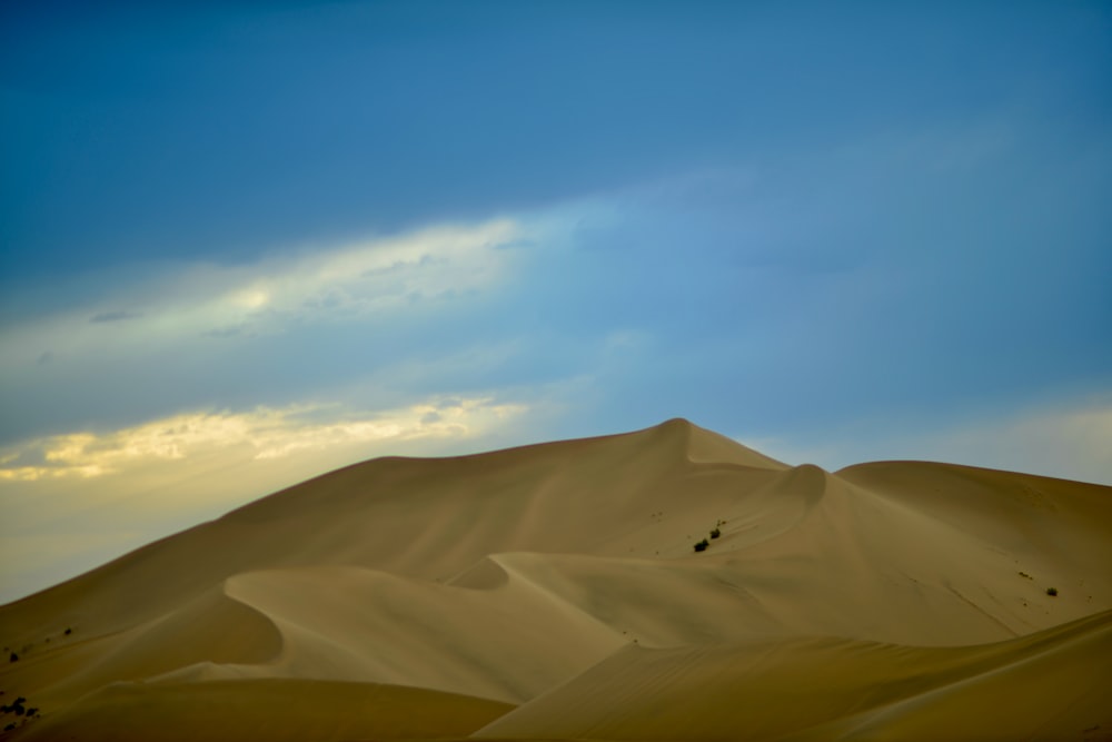 a hill of sand with a sky in the background