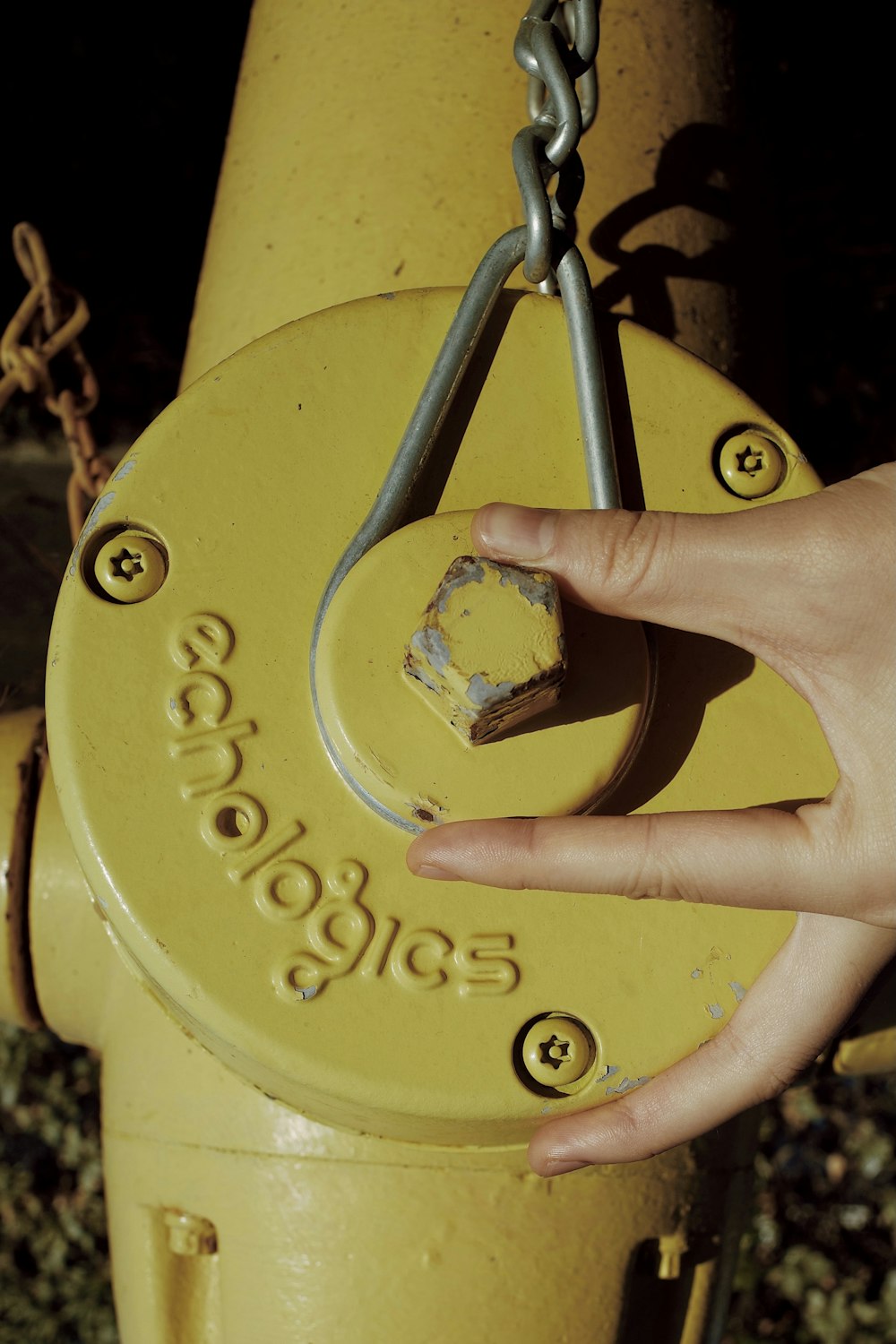 a person's hand on a yellow fire hydrant