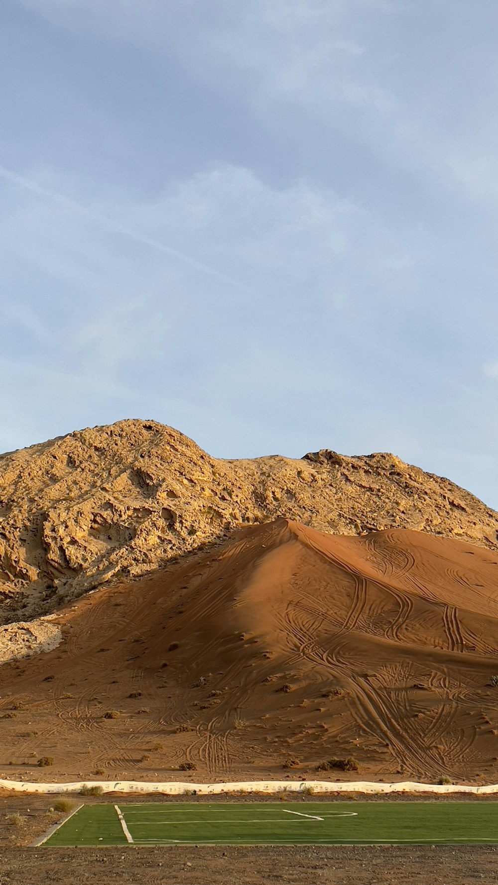 a plane flying over a desert with a mountain in the background