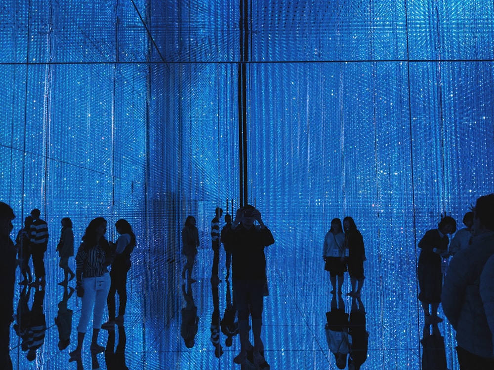 a group of people standing in front of a blue wall