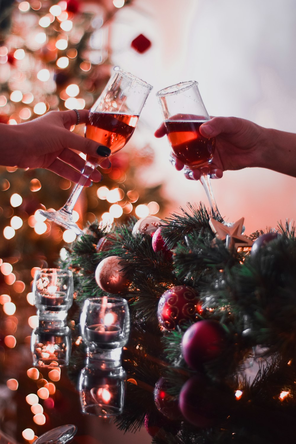 two people toasting with wine glasses in front of a christmas tree