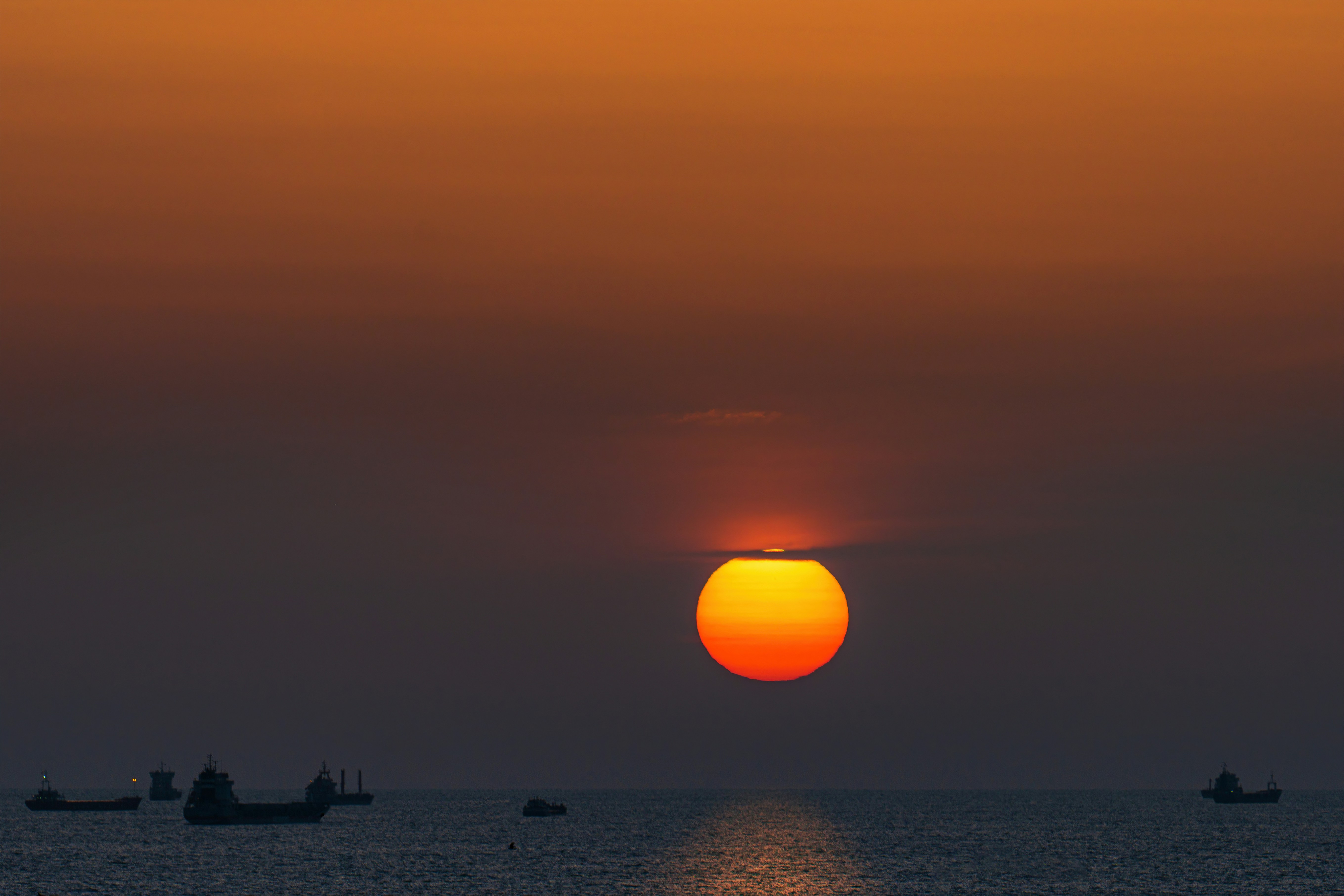 a sunset over the ocean with boats in the water