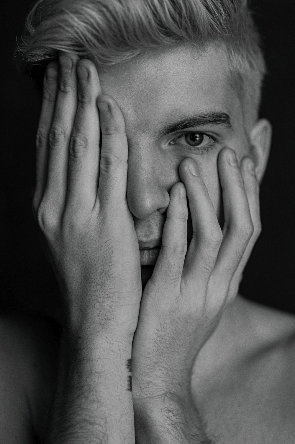 a black and white photo of a man holding his hands to his face