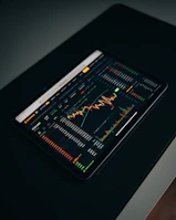 Close-up of hands analyzing financial charts and graphs on a tablet.
