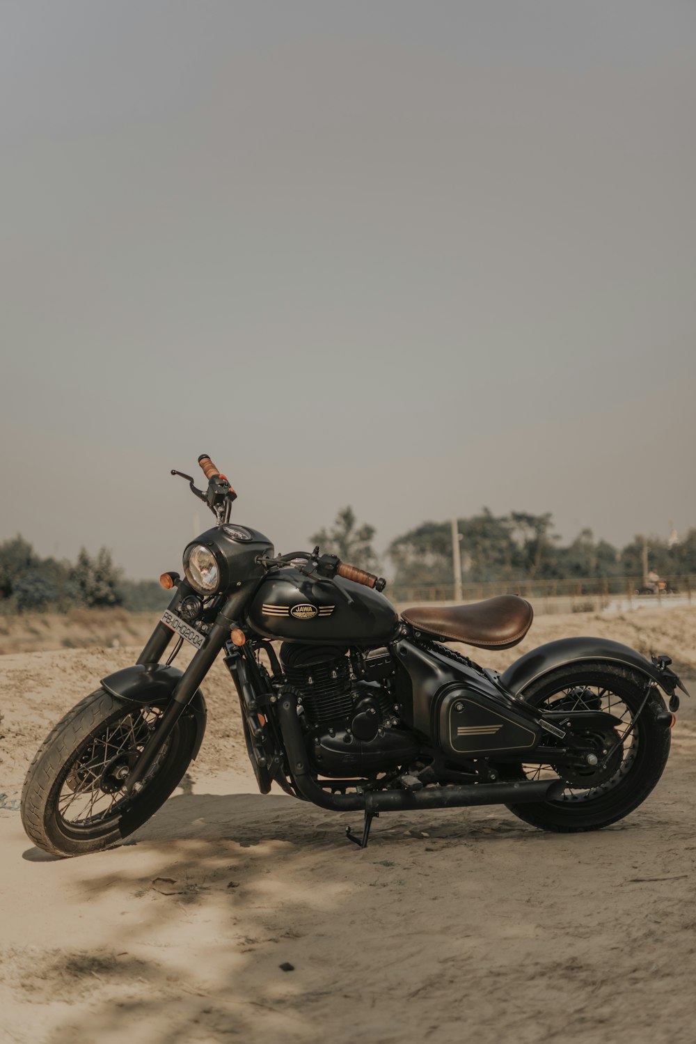 a black motorcycle parked on top of a sandy beach