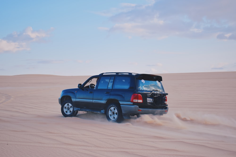 a blue truck driving through a sandy area