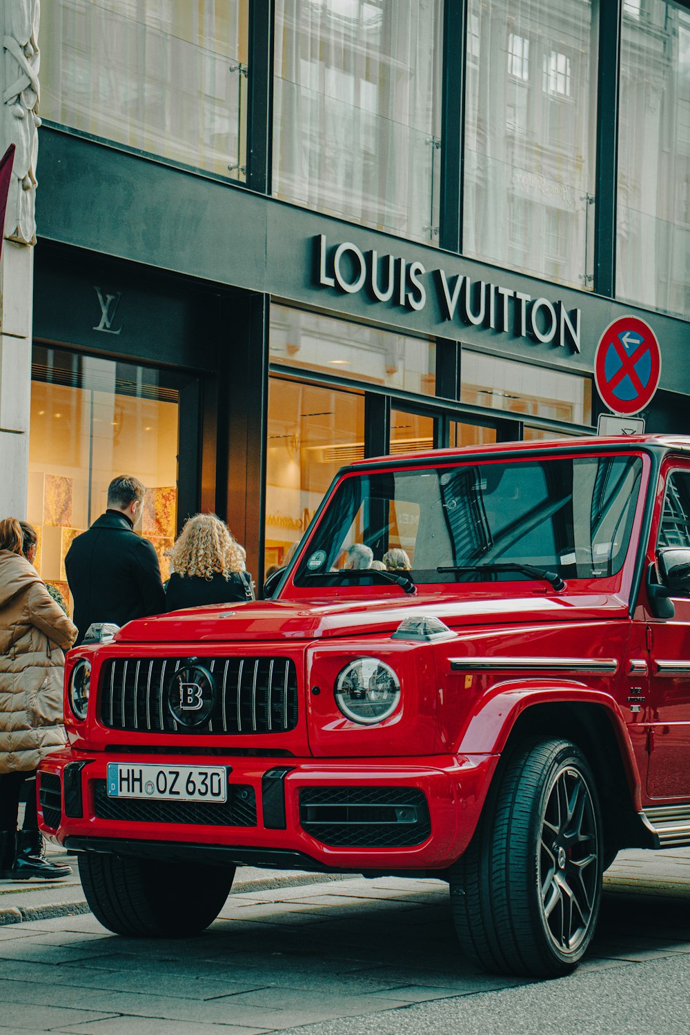 a red jeep parked in front of a louis vuitton store