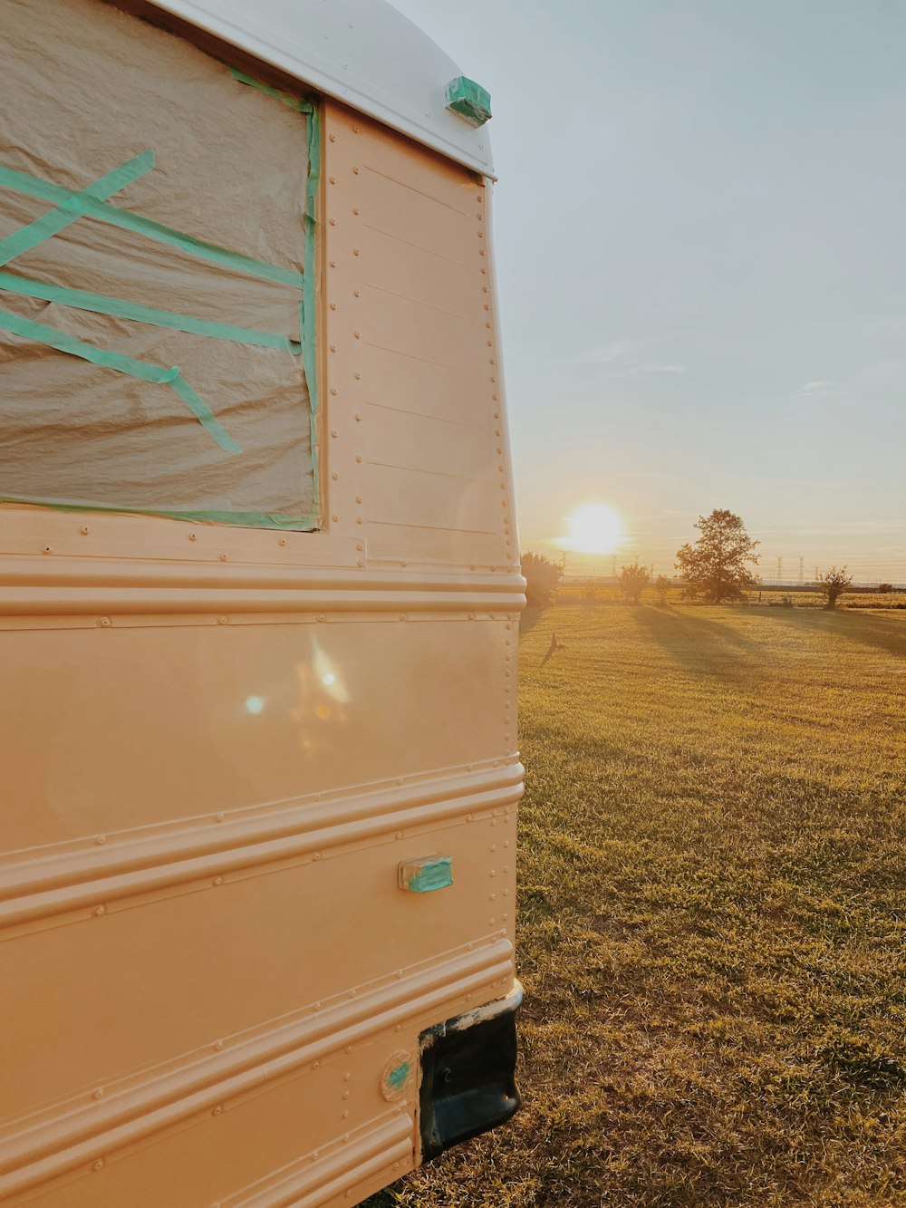 the sun is setting behind a trailer in a field