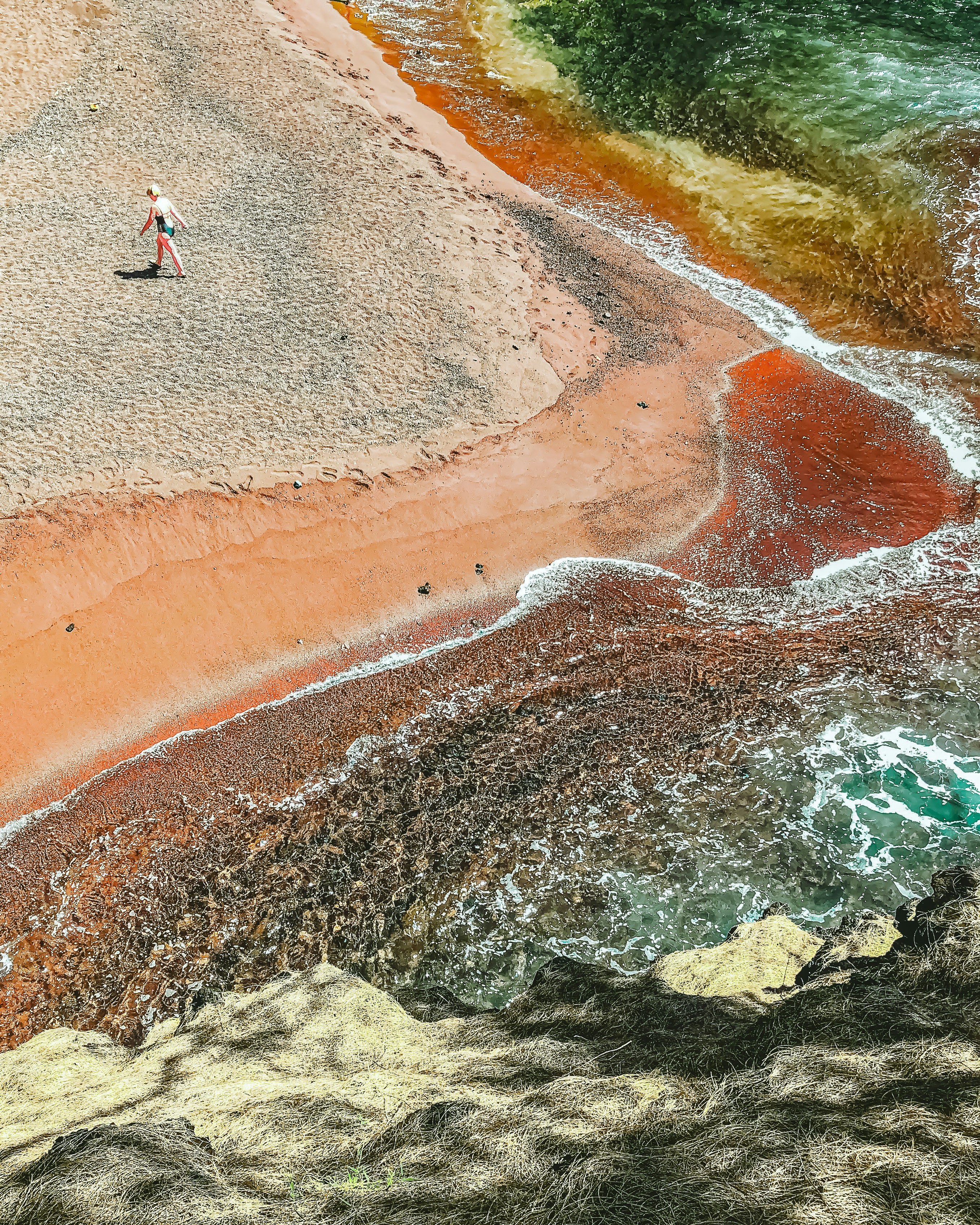 an aerial view of a man walking on a beach