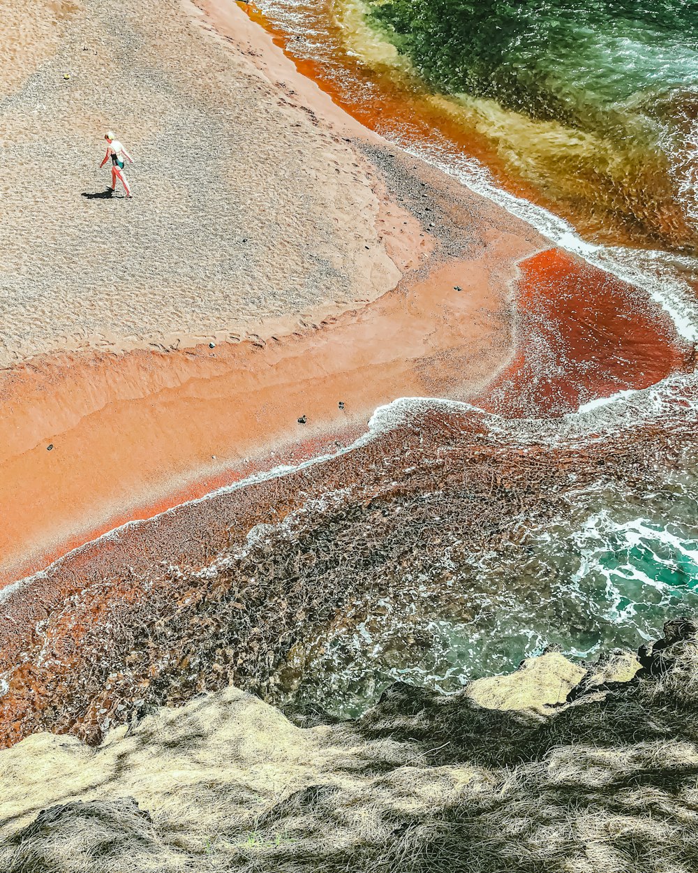 an aerial view of a man walking on a beach