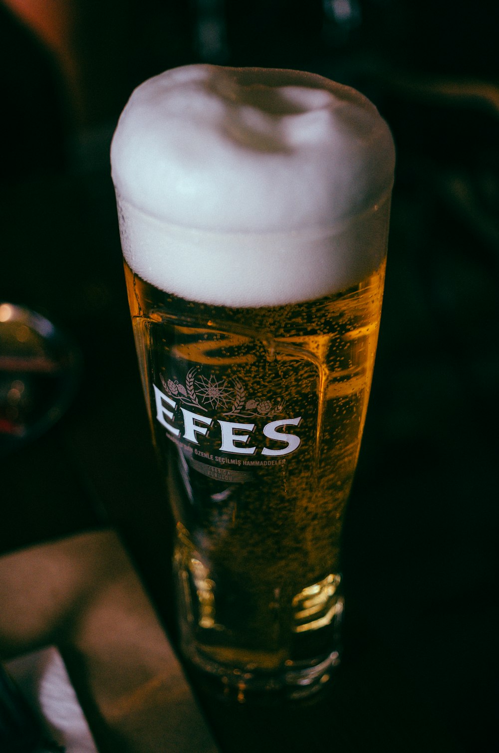 a glass of beer sitting on top of a table