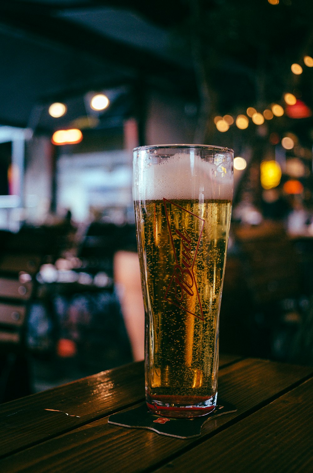 a glass of beer sitting on top of a wooden table